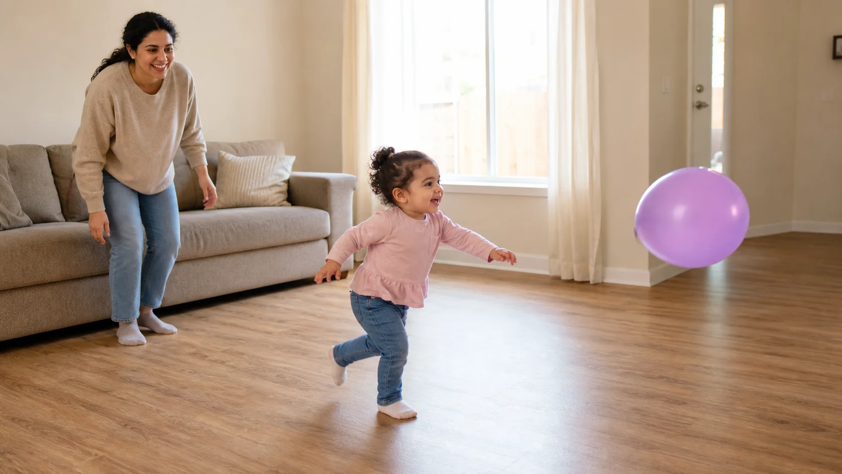 A toddler runs across a living room after an untied balloon while a grown-up watches nearby.