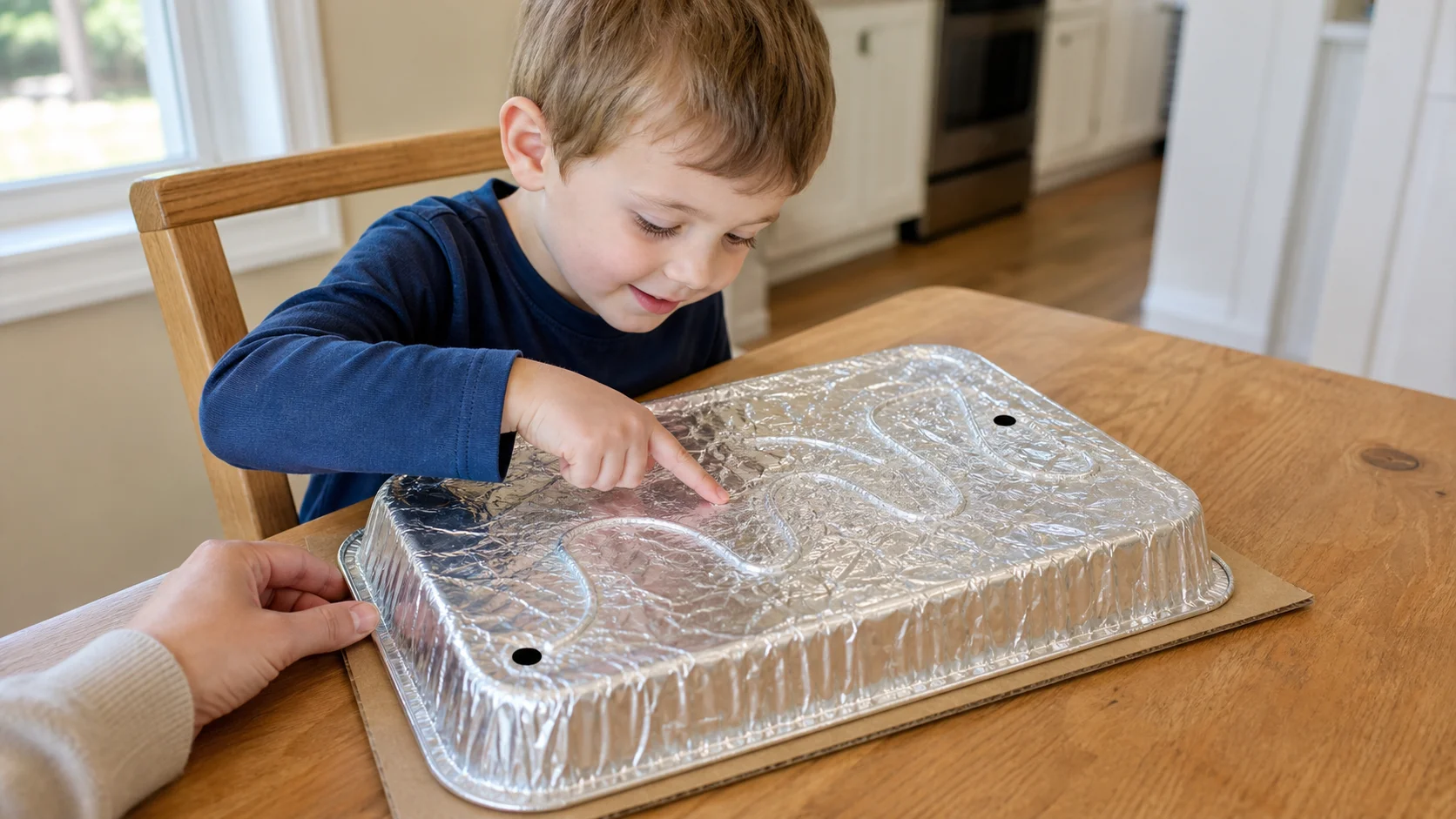 A child tracing a raised yarn path hidden under a foil pan with one pointer finger.