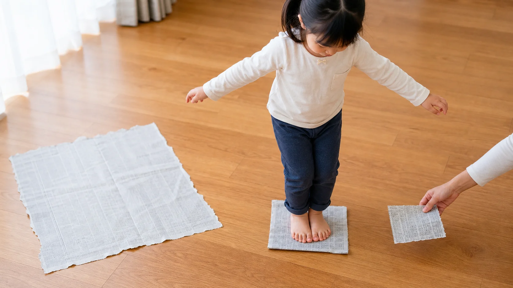 Preschool child standing on a newspaper sheet on the floor while a grown-up sets down the next smaller paper island.
