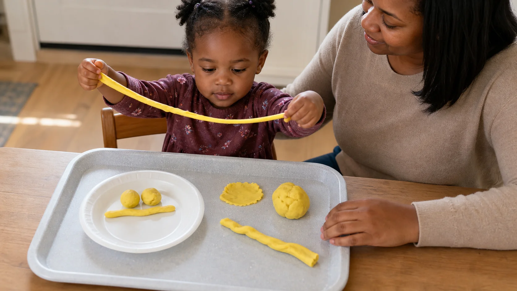 A child pulling playdough noodles and rolling meatballs on a child-safe plate.