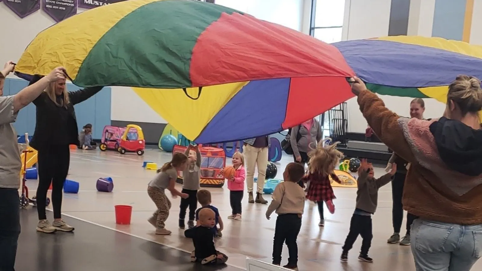 Children riding scooters at the Andover Tot Time open gym