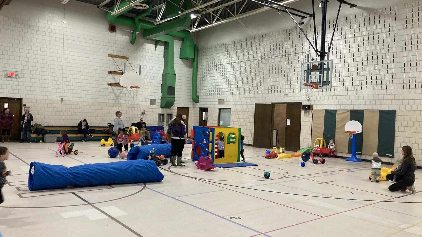 Children playing with balls and scooters in a rec center gym