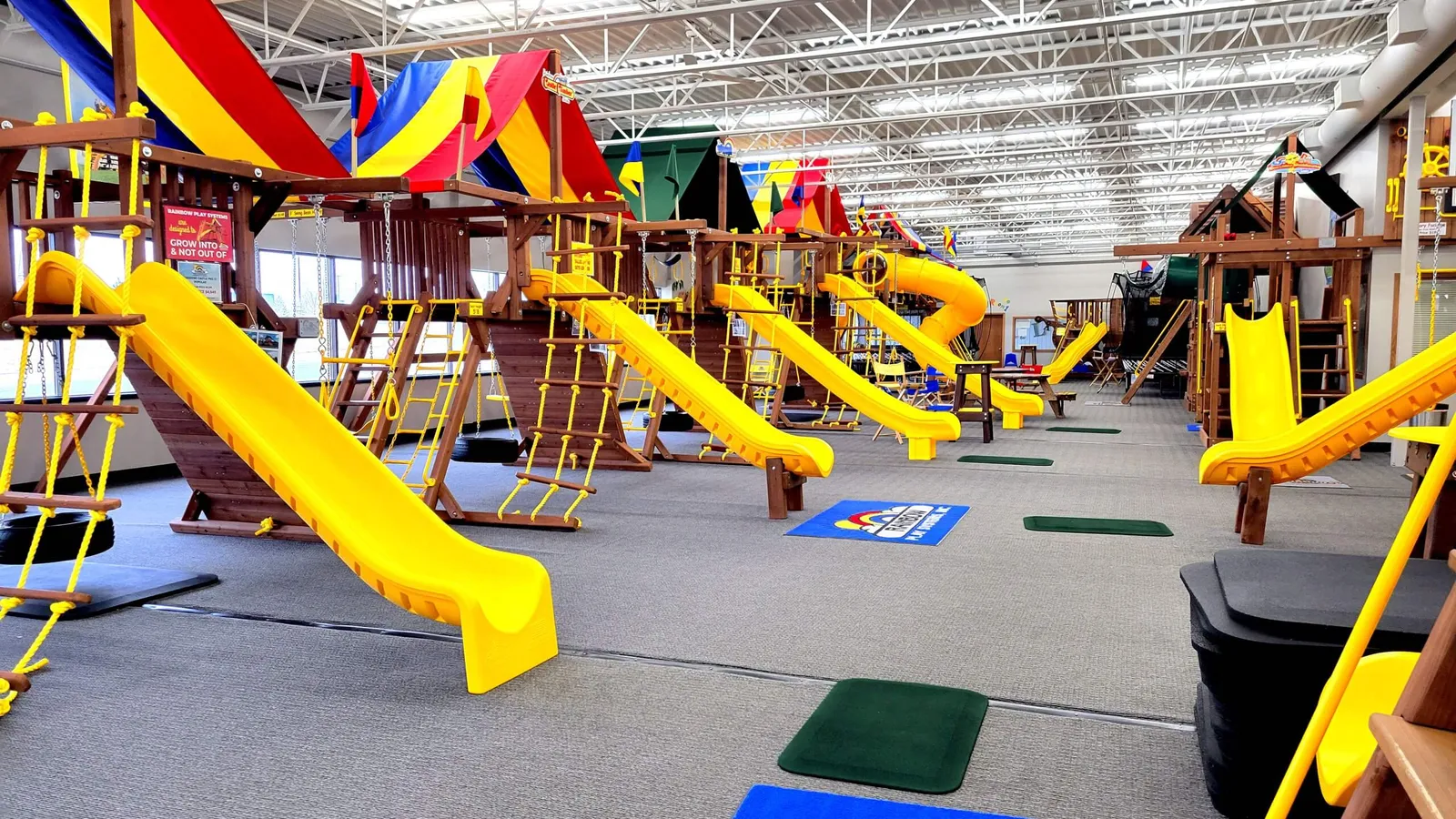 Children sliding on a Rainbow playset inside the showroom
